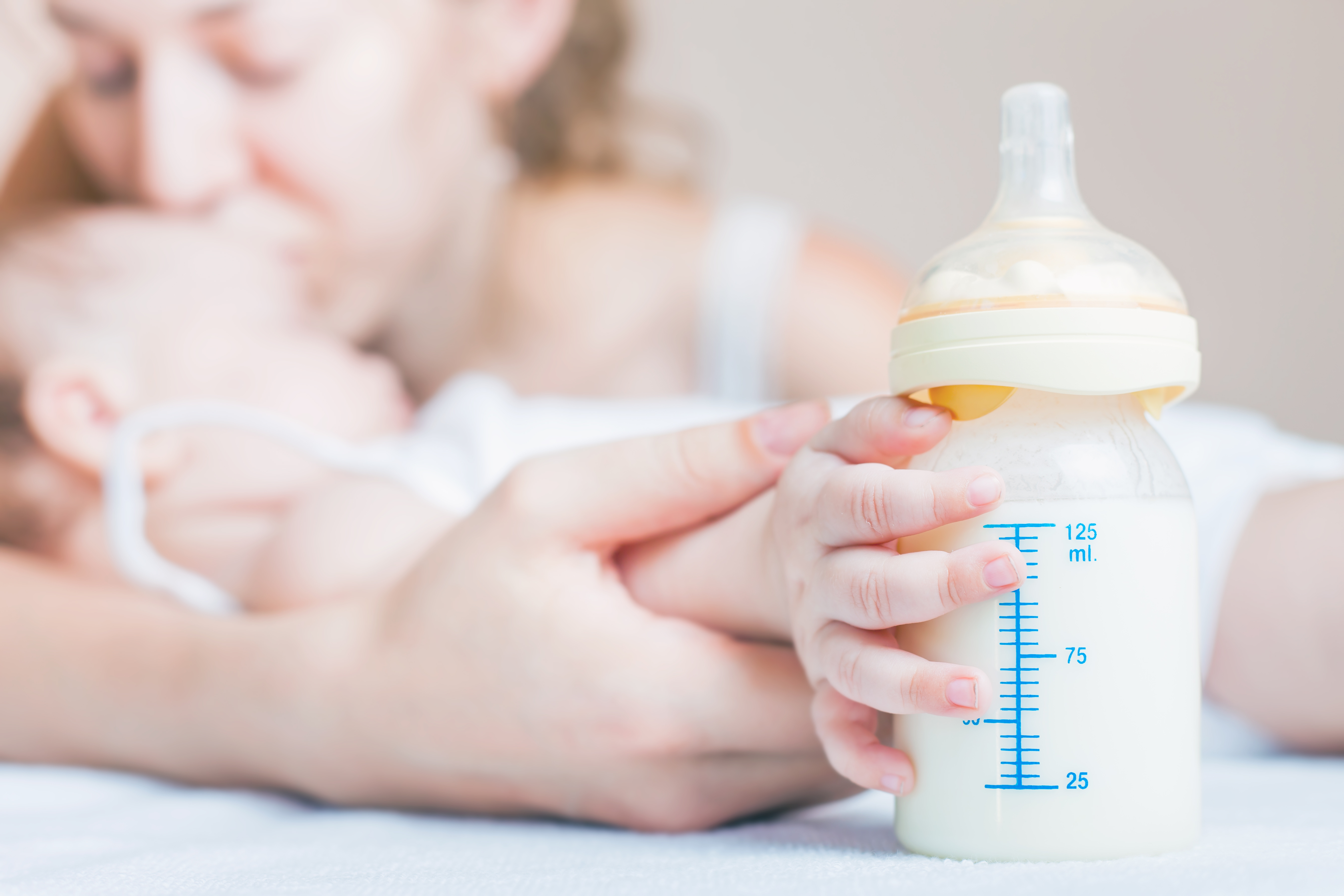 Baby holding a baby bottle with breast milk