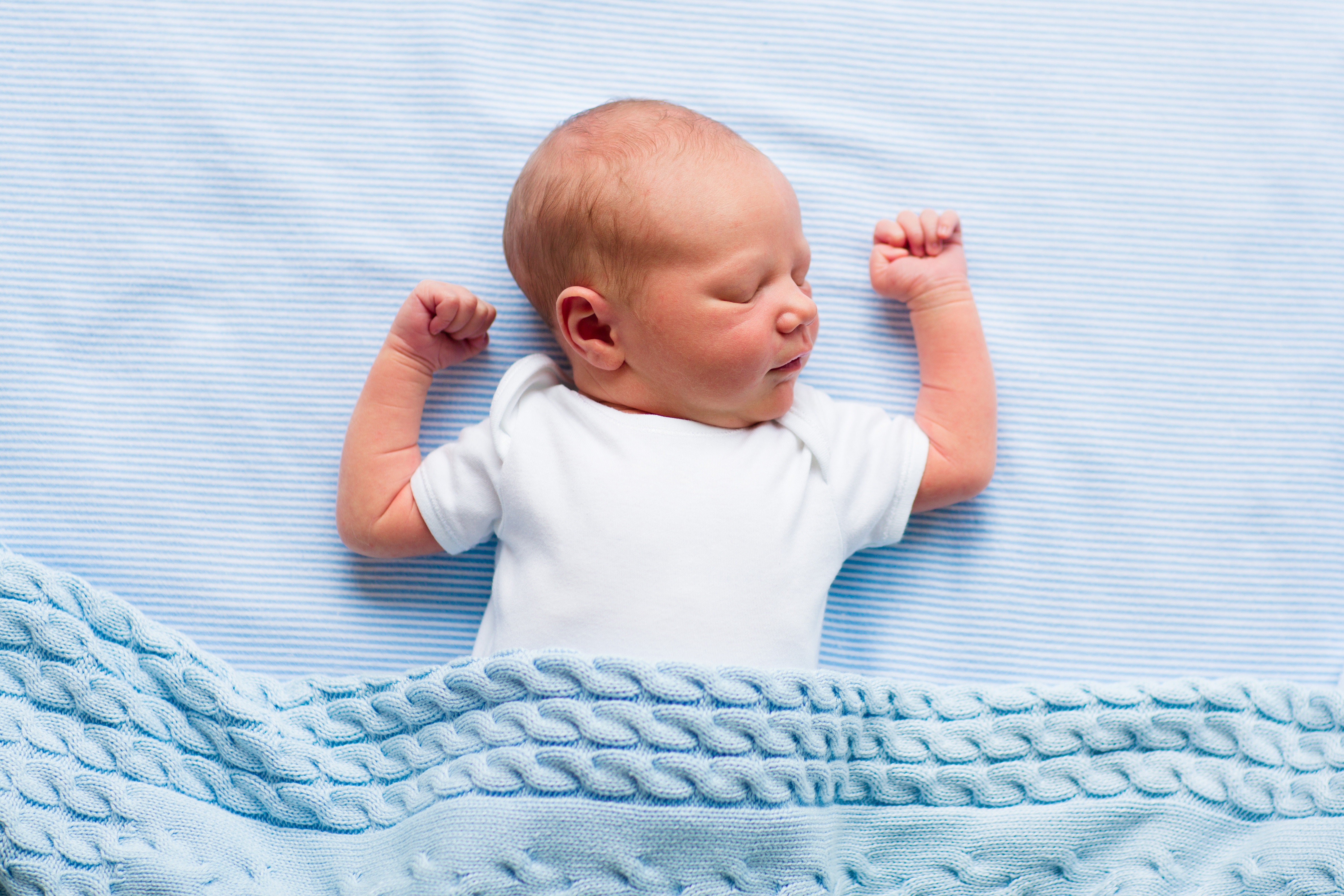 Newborn baby boy under a blue blanket