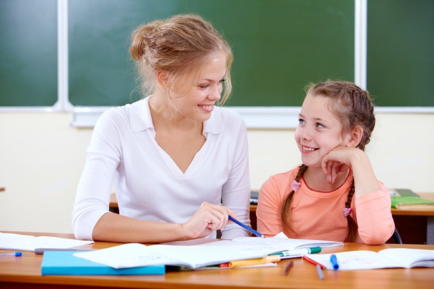 teacher-helping-young-girl-with-writing-lesson_1098-1861